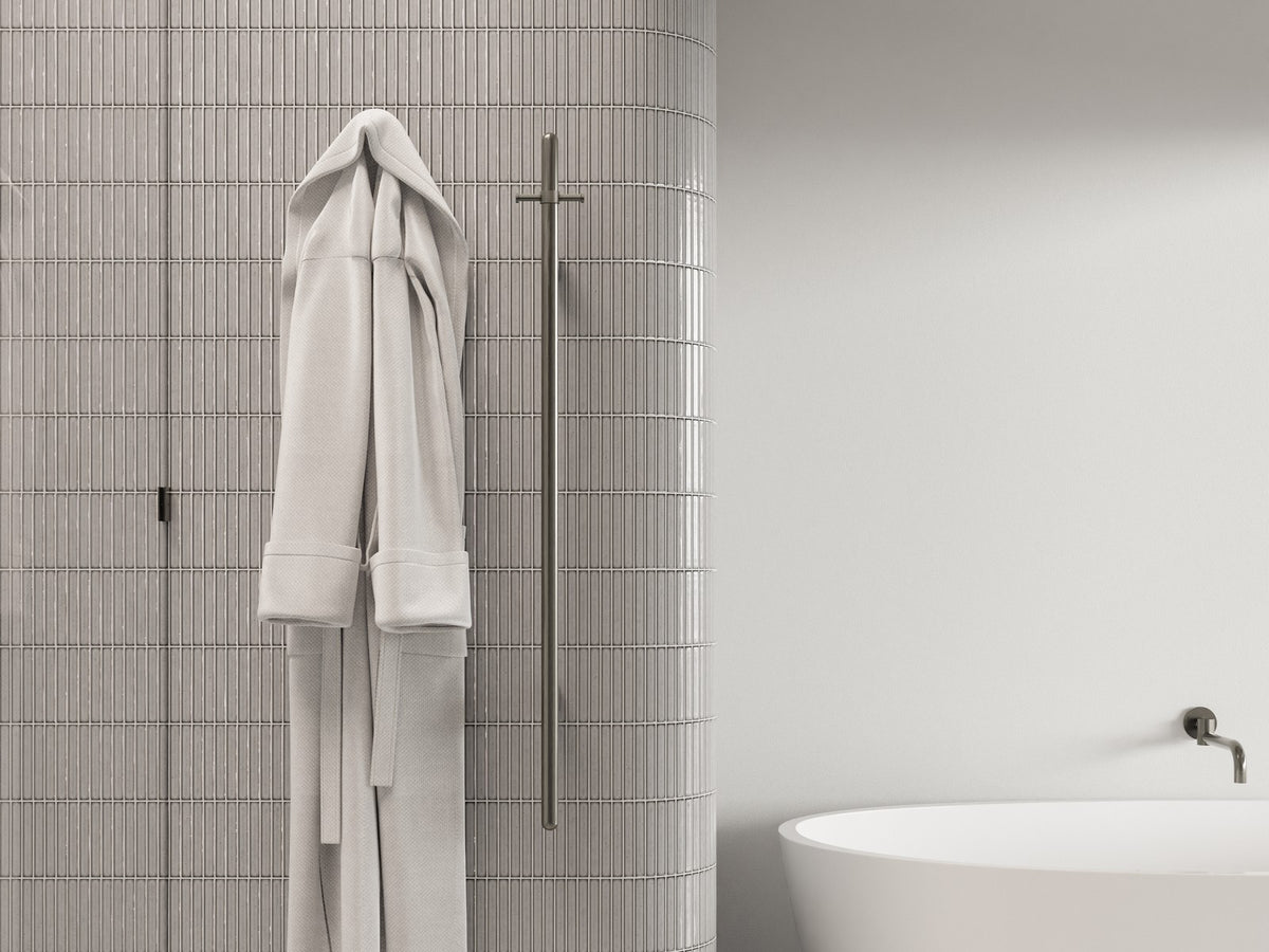 Meir heated towel rail with robes beside a freestanding bath