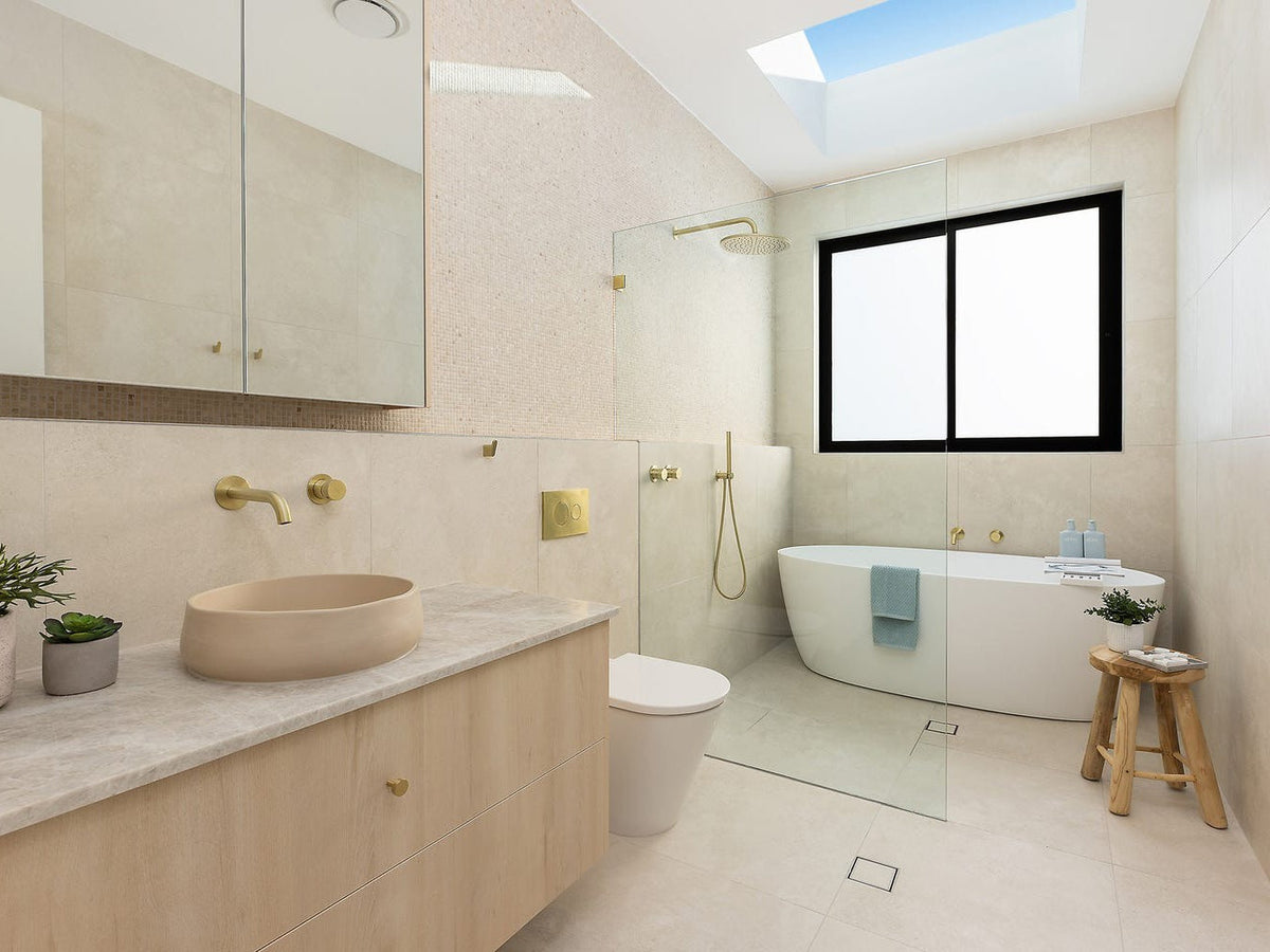 Sunkissed Sans Souci bathroom with warm white terrazzo-look floor, freestanding bath and timber vanity