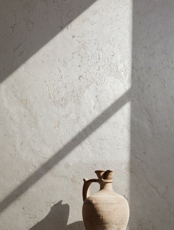 Luberon Cream limestone look porcelain wall in raking sunlight with a terracotta jug