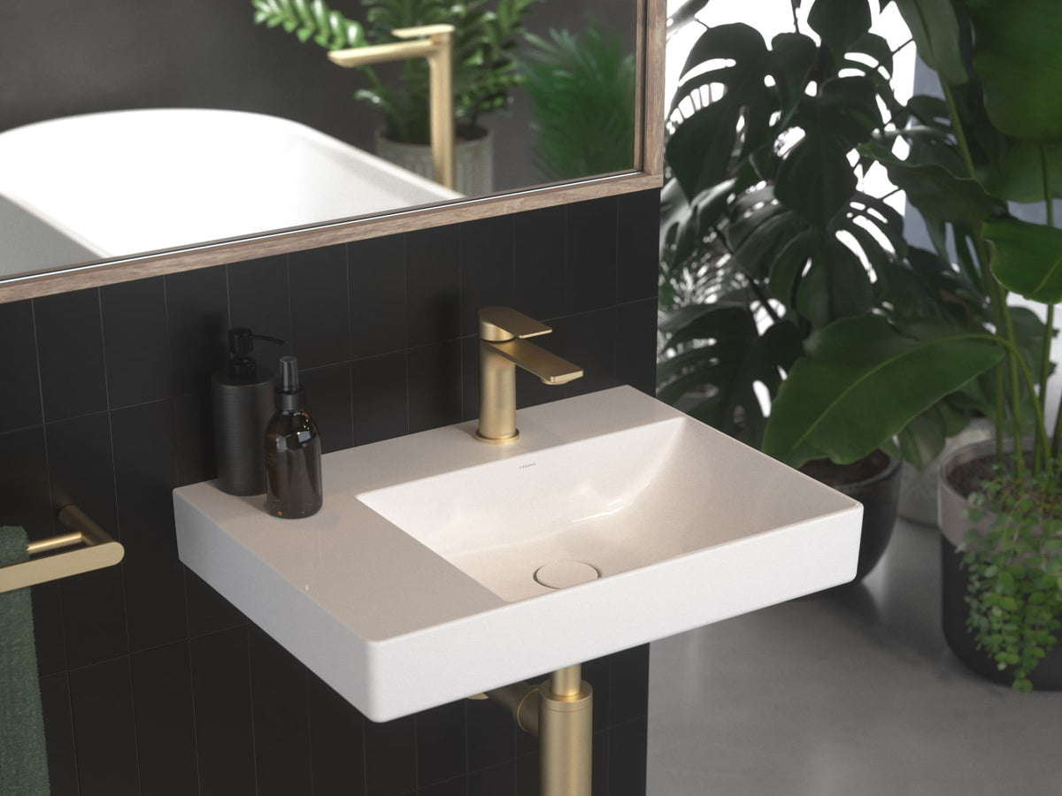 Brushed brass bathroom shelf and wall hung basin against a dark wall
